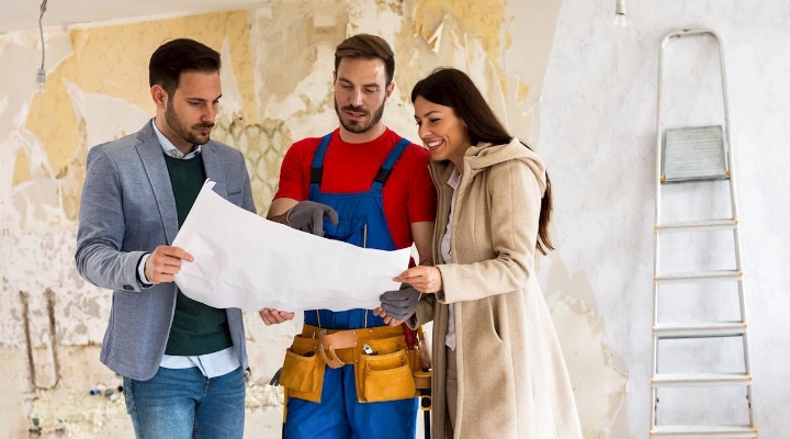 Three people looking at construction blueprint