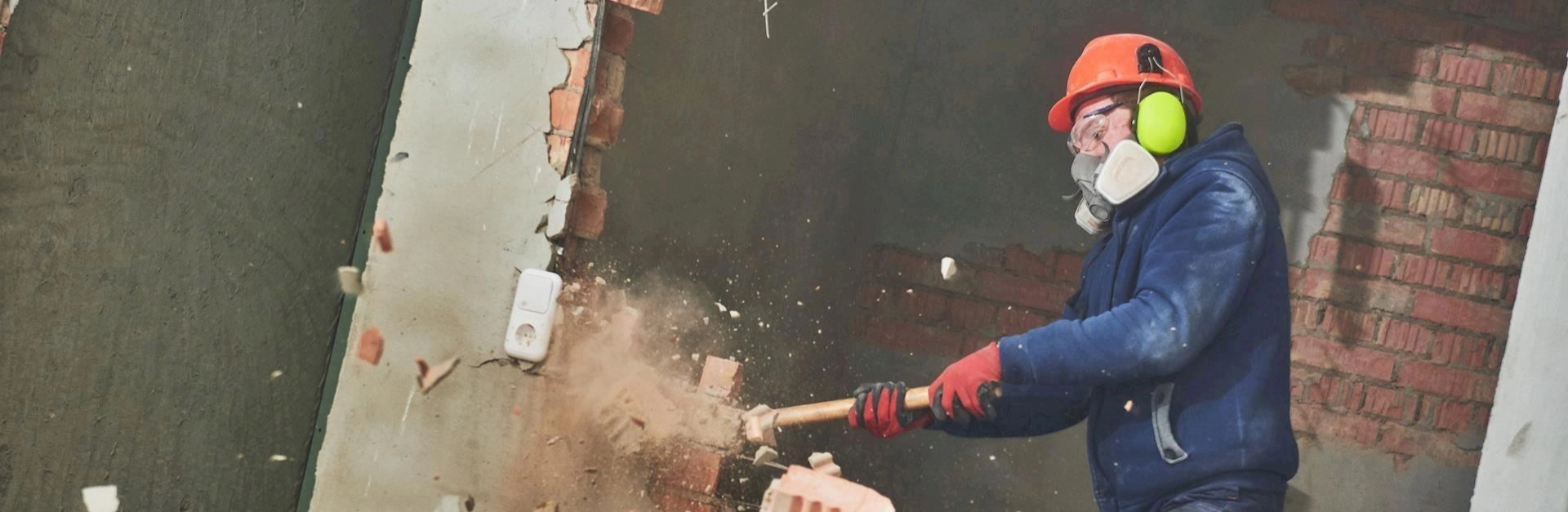 Construction worker breaking wall with sledgehammer